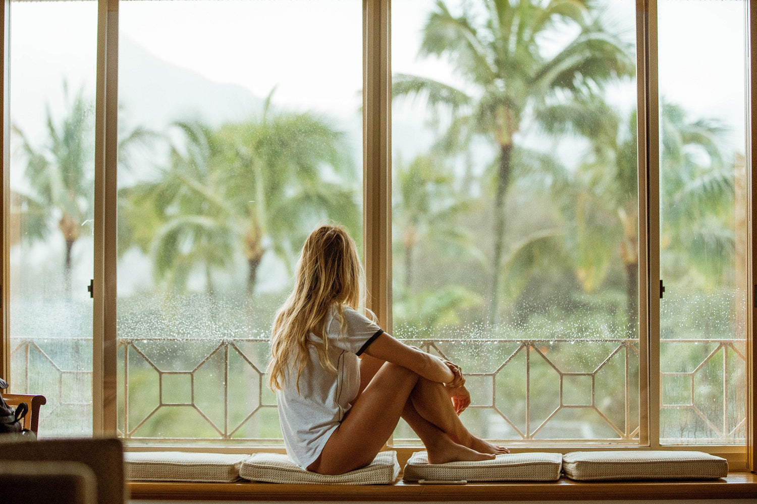 jeune femme en t-shirt regardant le paysage tropical par la fenêtre