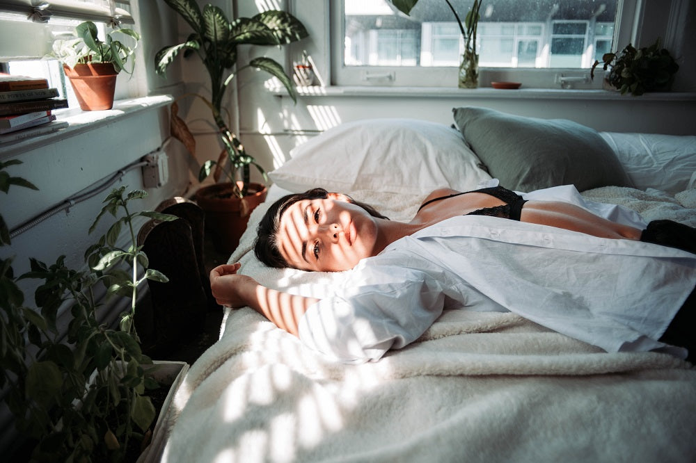 jeune femme allongée sur son lit avec un rayon de soleil