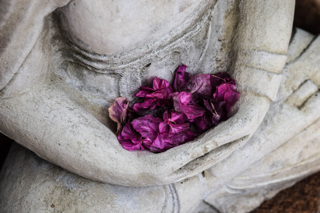statue du bouddha qui tient des fleurs en offrande dans ses mains